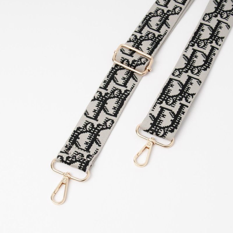 Skulderrem grå og svart - mønstret veskereim med gullfarget metall